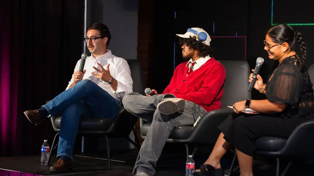 Three panellists on stage at The Model, microphones in hand, in front of the event's lighting rig
