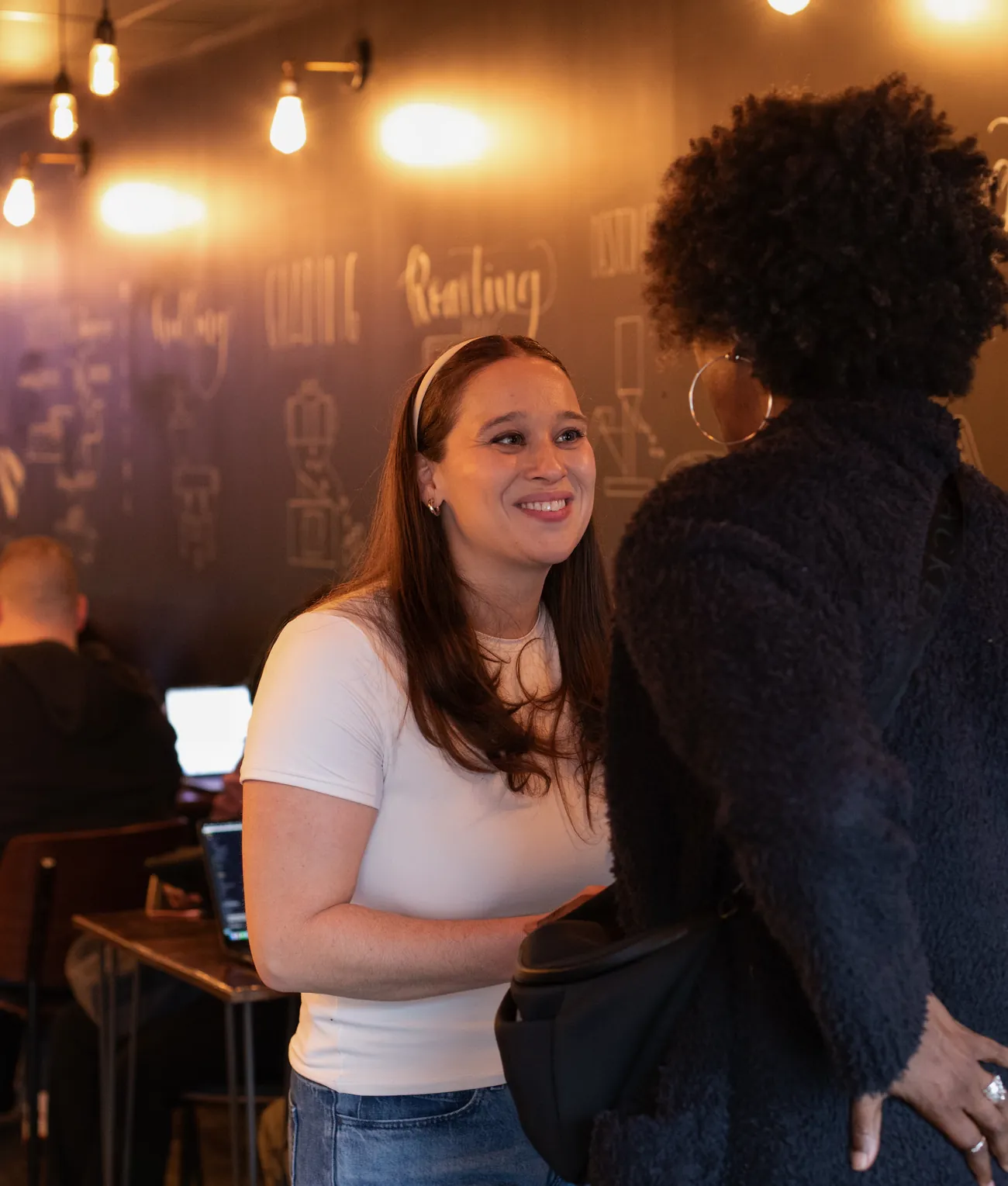 Laura Ruiz-Roehrs in conversation with an attendee at SheBuilds, a builder working at a laptop behind them